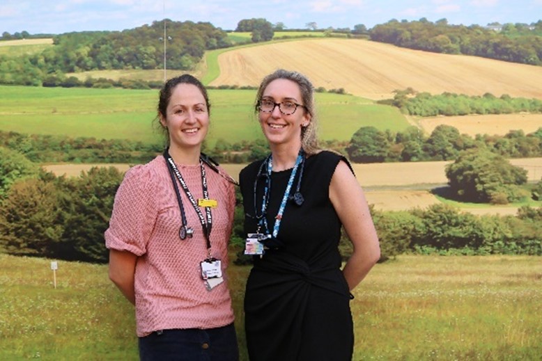A picture of Rachel Burridge, a consultant nurse for frailty (left) and Dr Katie Honney, the clinical director for Integrated Care of the Older Person (right) standing in front of a picture of a field with their stethoscopes on