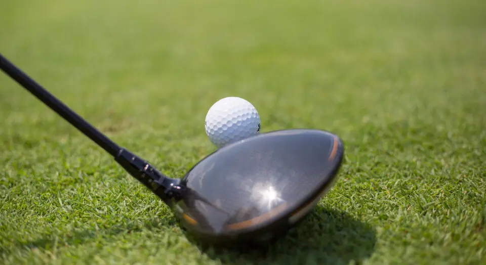 A picture of a club resting against a golf ball