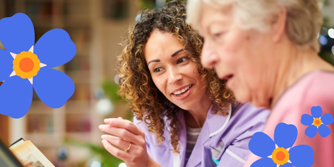 A picture of a woman showing an elderly woman a photo album. the forget-me-not graphic can be shown on the image as well