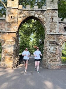 A photo of two young women (Tabitha & Sam) running through stone arches