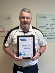 Gavin Brooke holding his framed award certificate