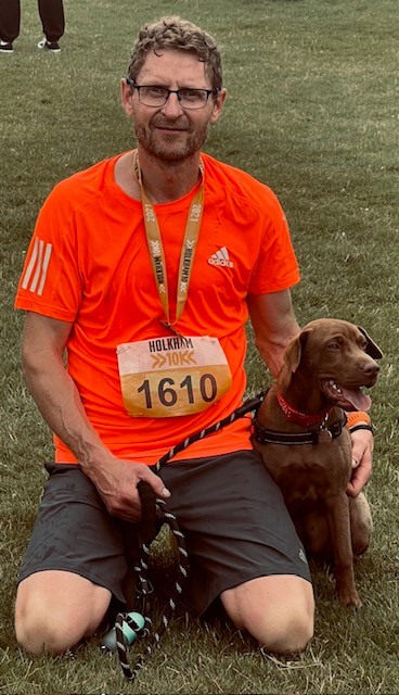 Stephen Timberlake with a running medal on the grass with his dog